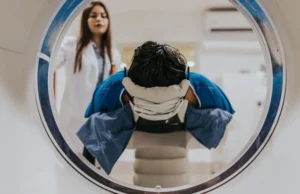 Paciente prepar&aacute;ndose para una resonancia magn&eacute;tica abierta, guiado por una t&eacute;cnica especialista en diagn&oacute;stico por imagen.