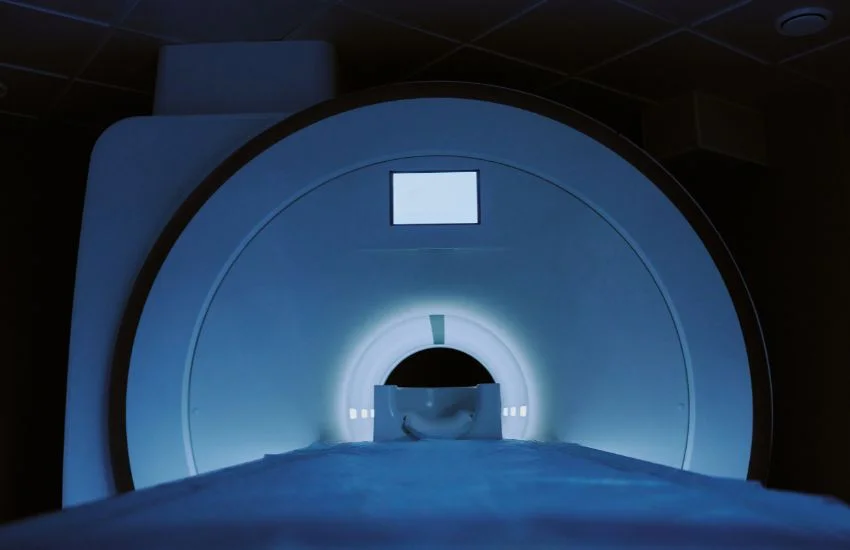 Equipo de resonancia magnética en una sala clínica, con la camilla de exploración entrando en el escáner, usado en pruebas diagnósticas como la resonancia magnética de dedos.